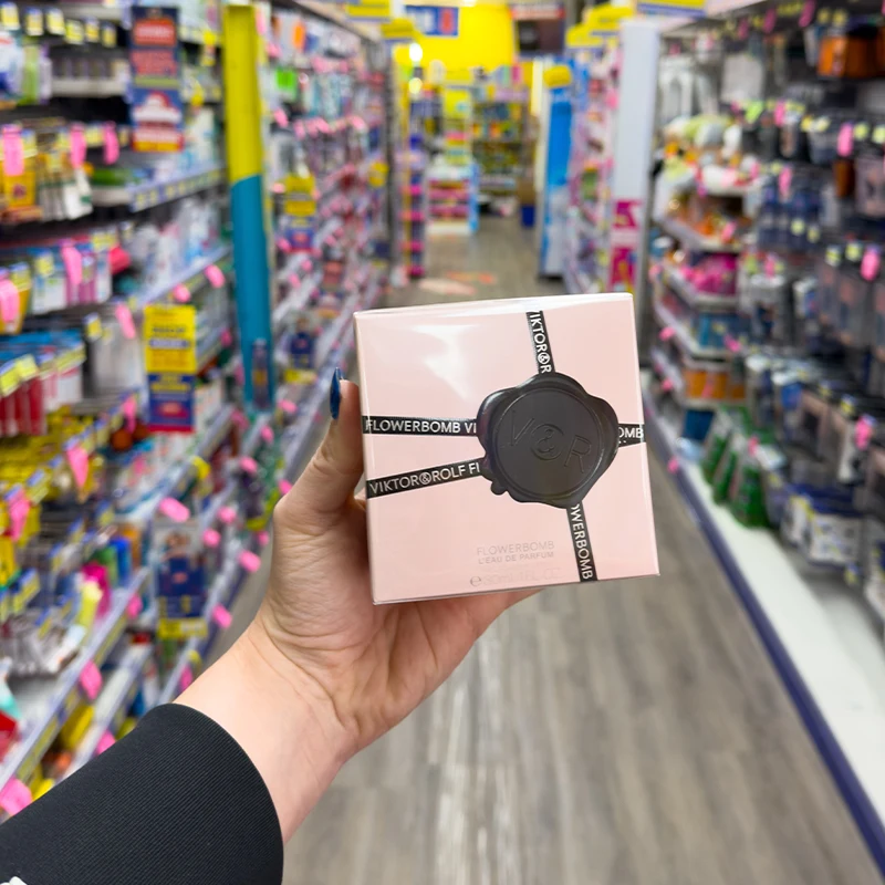 Hand holding Viktor&Rolf Flowerbomb perfume box in rose gold with black wax seal.