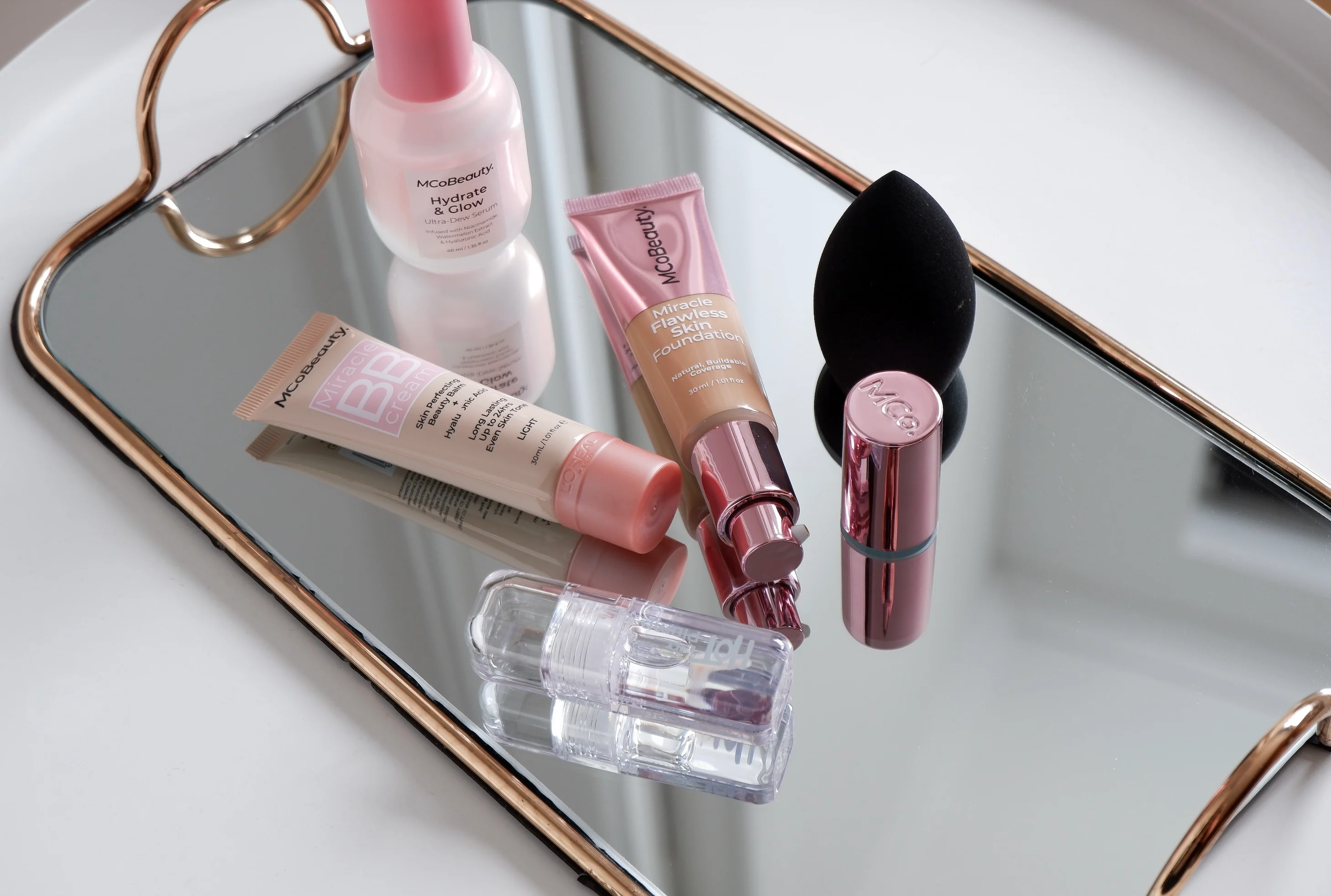 Cosmetic products and bb creams on a mirrored tray.