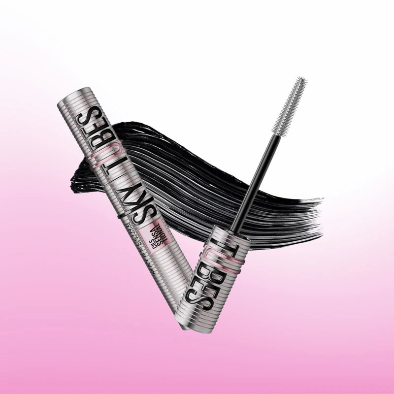 Silver mascara tube labeled Lys Tubes with open wand applicator, black mascara smear on pink-white gradient background.
