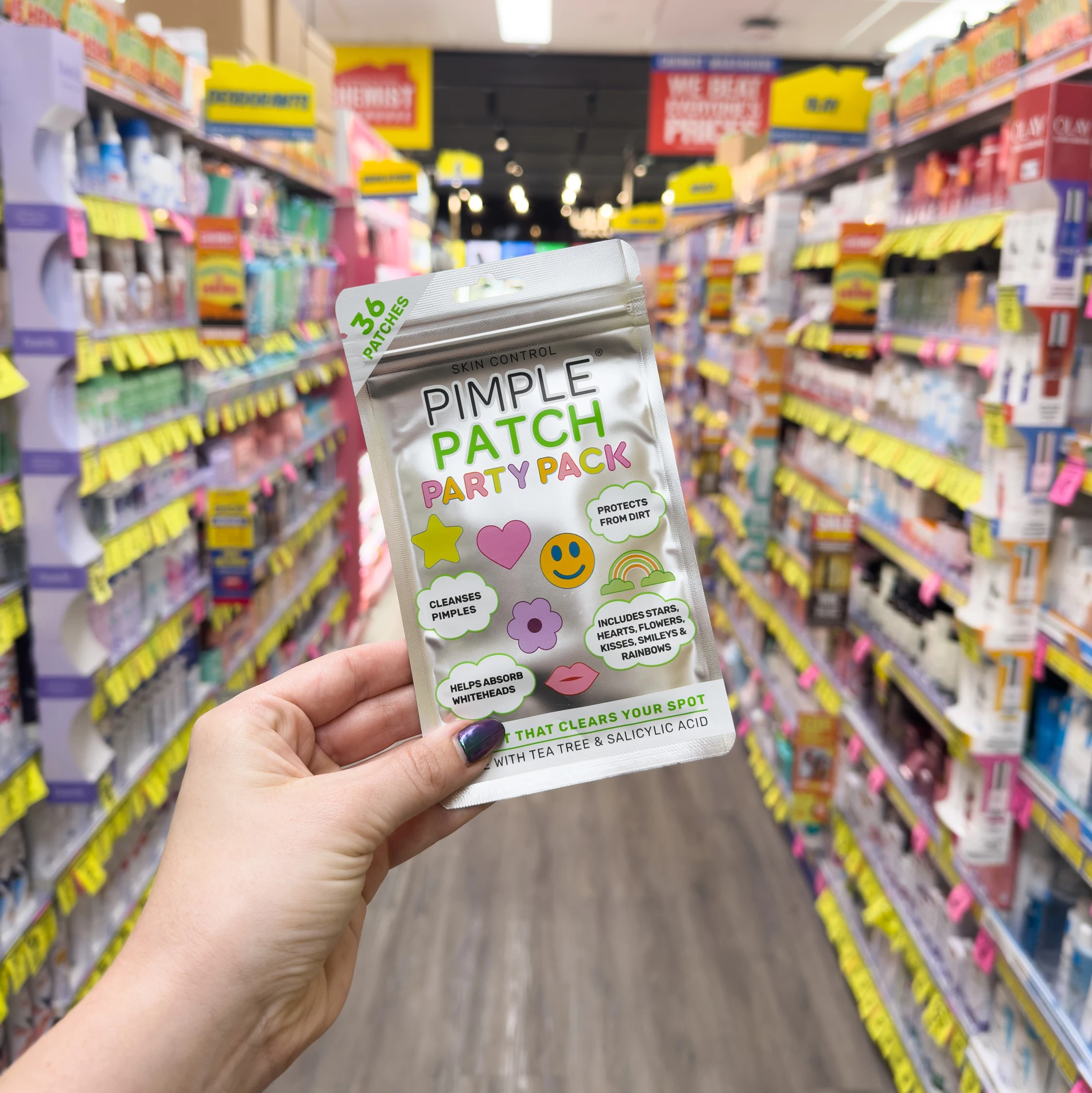 Hand holding decorative Pimple Patch Party Pack in retail store aisle with colorful product displays in background