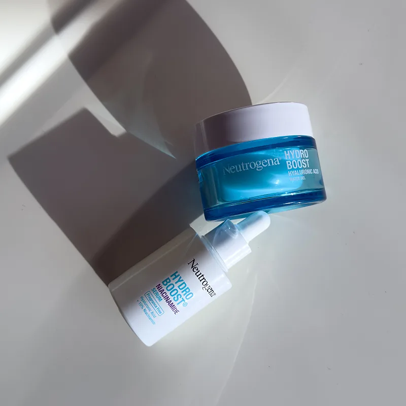 Two Neutrogena Hydro Boost skincare products with blue and white packaging casting dramatic shadows on a white surface.