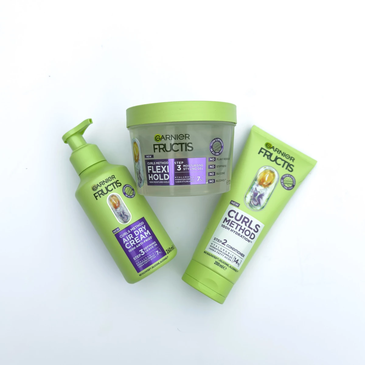 Three Garnier Fructis Curls Method products in green packaging: Air Dry Cream, Flexi Hold Styling Gel, and Curls Method Conditioner.