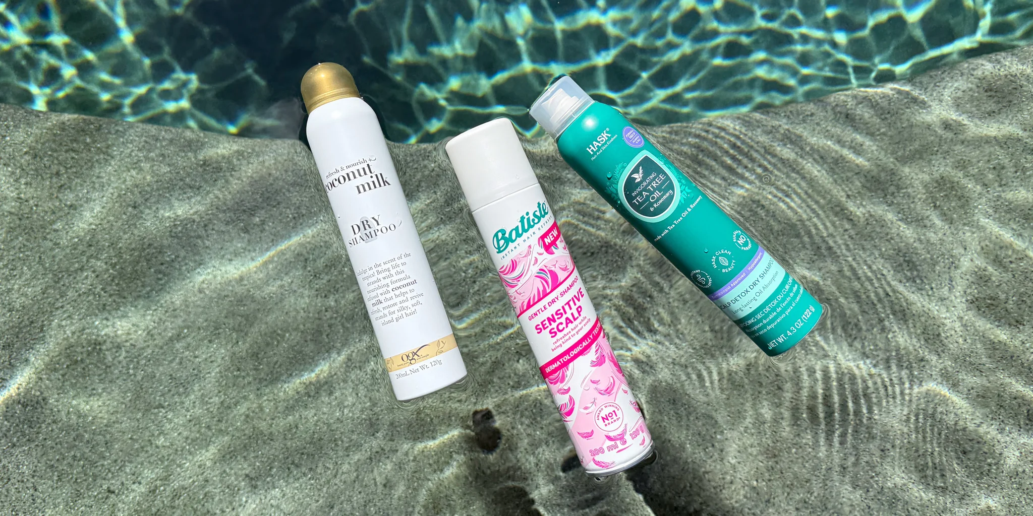 Three dry shampoo bottles lying on pool steps underwater, with rippling water patterns visible in the background.