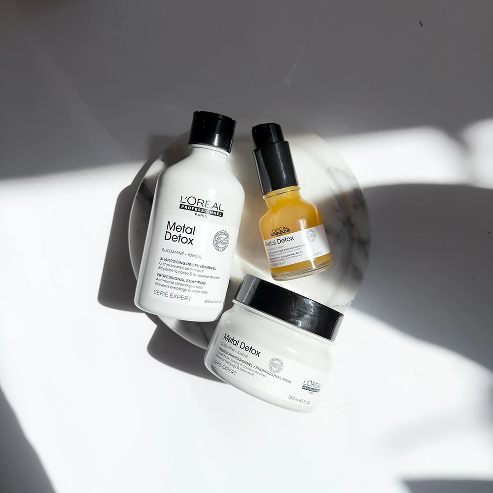 L'Oreal Metal Detox hair care products including shampoo, mask, and serum bottles on white background with dramatic shadows