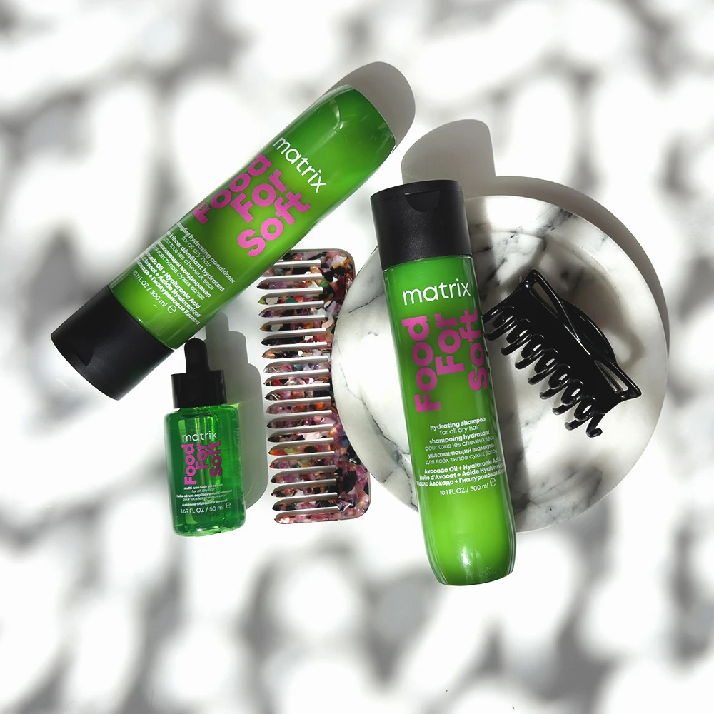 Green Matrix Total Results hair care bottles arranged with a decorative hair clip against a soft white background