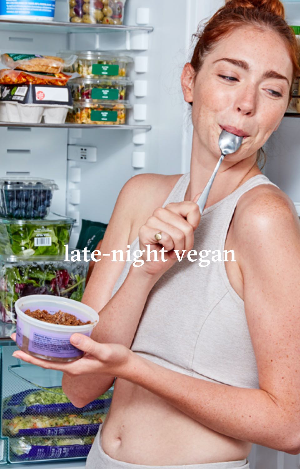Woman in front of an open refrigerator eating from a container with a spoon in her mouth. Headline reads Late-night Vegan