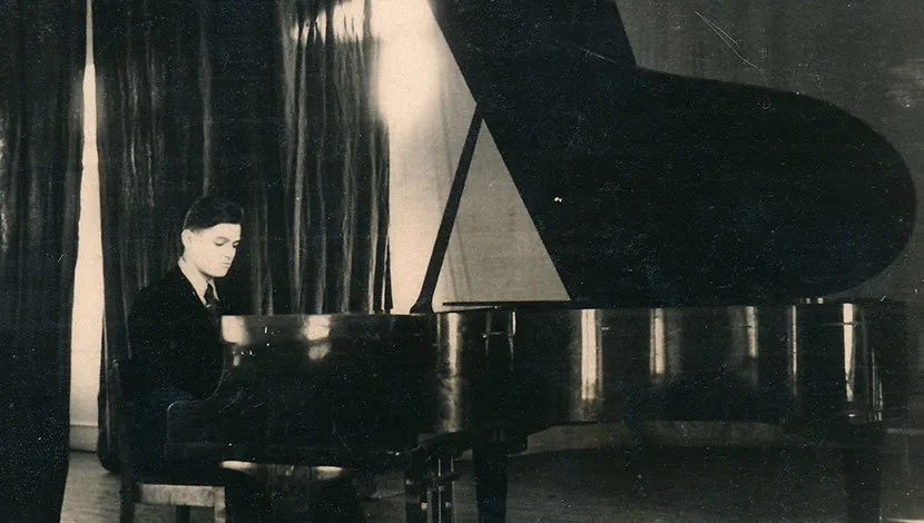 black and white photograph of a young man playing a piano