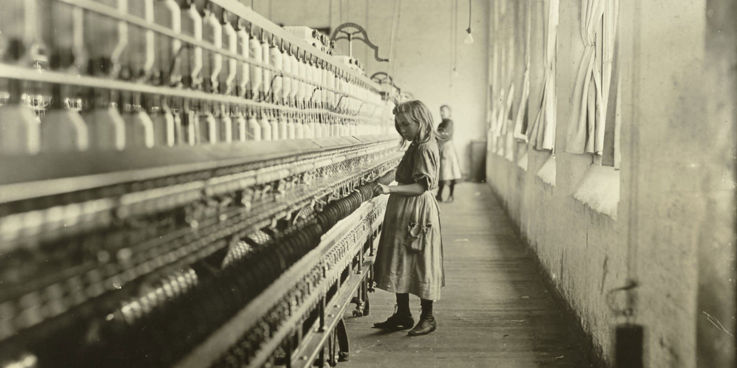 black and white photograph, a young girl working at a cotton mill.