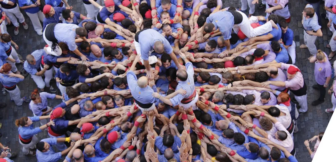 A crowd of people with outstretched arms, which others are climbing onto