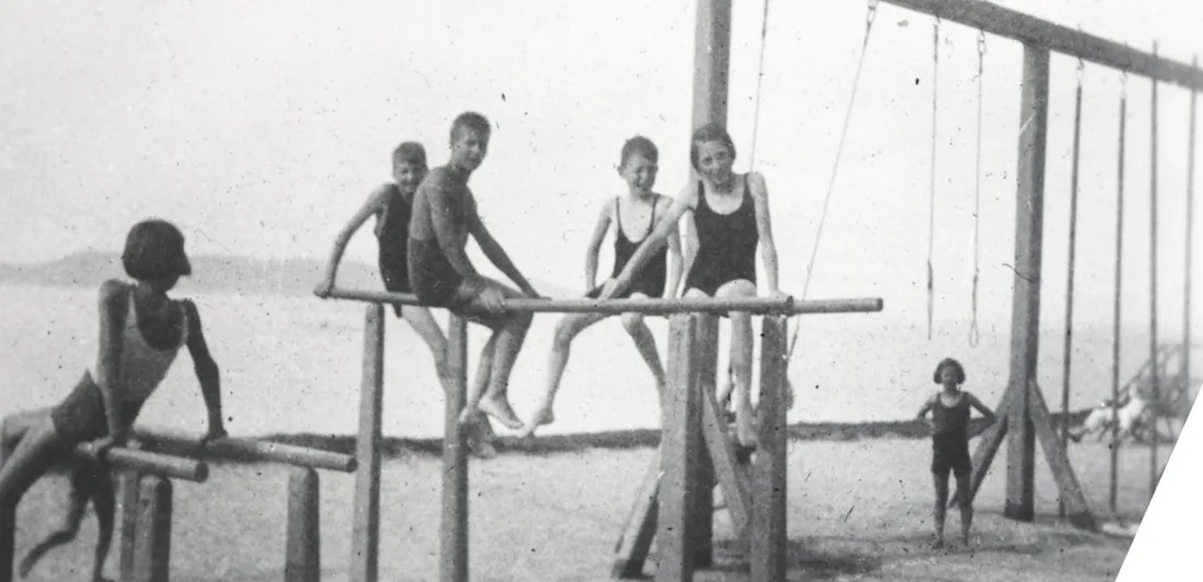Children doing gymnastics on bars on a beach