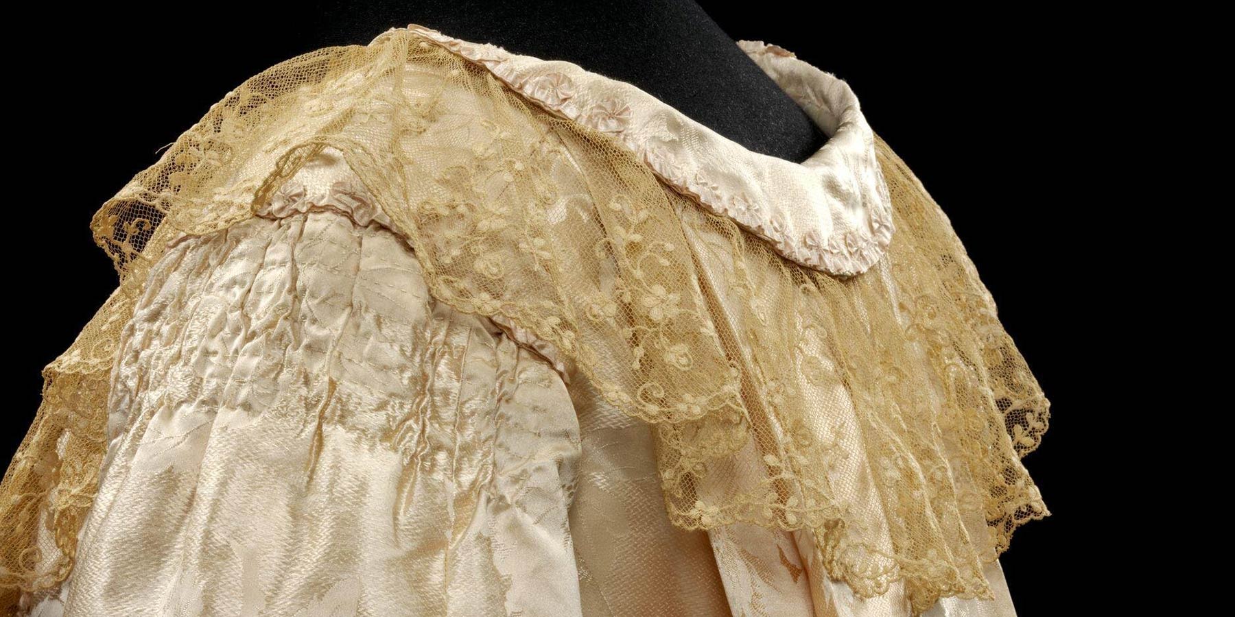 close-up of an ivory lace shawl with floral embroidery on a mannequin.