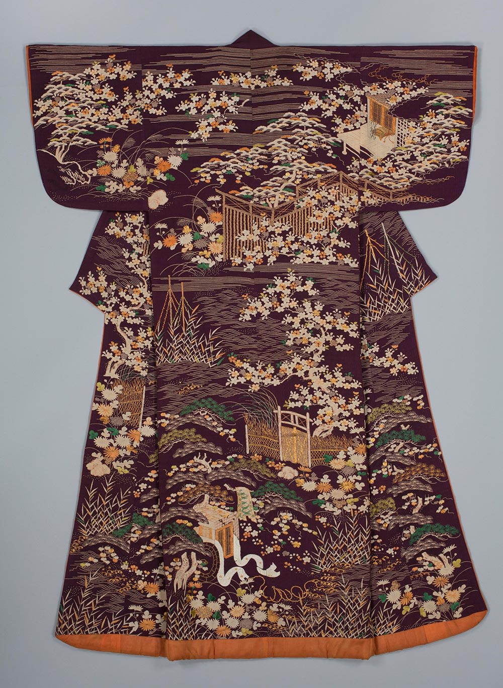 colour photograph of a brown kimono with a design showing a landscape with pavilion, gateway, fishing nets and nobleman’s cart