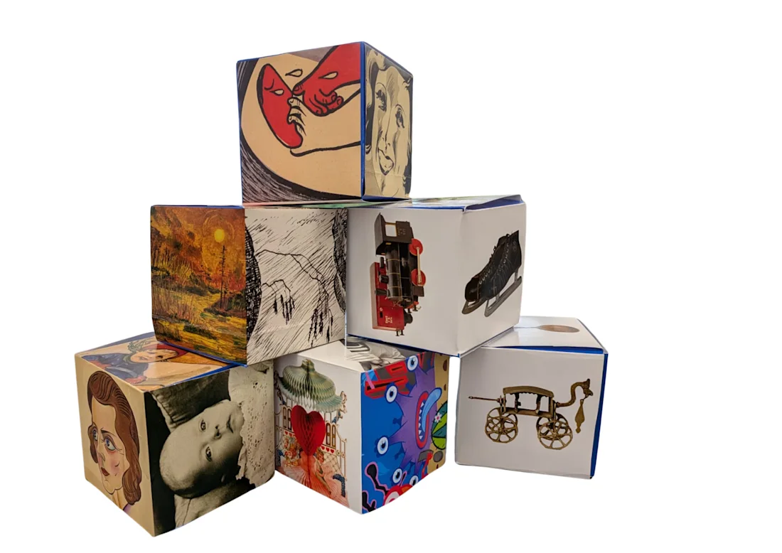 Six decorated cubes with various artistic images and drawings stacked together on a white background.