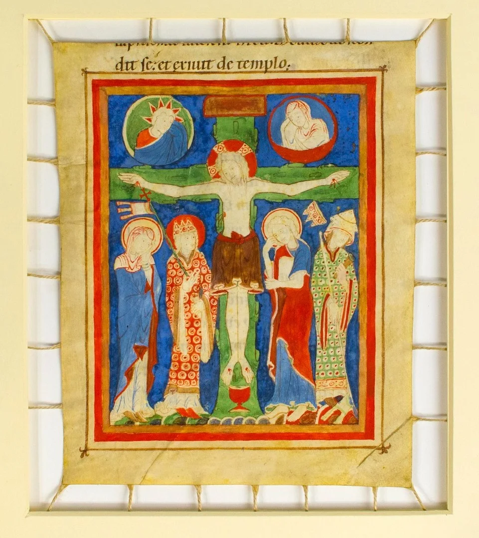A manuscript in vellum from a book of Pericopes. The scene shows Christ crucified, a chalice filling with blood below his feet. Standing beneath the cross on the right of Christ is Ecclesia carrying a standard and torch. Beside her stands the Virgin Mary in a blue cloak. On the left stands St John and a personified Synagoga with a crown falling from her head, a trailing banner and extinguished torch in her hands. Above the cross are figures representing a mourning sun and moon. The script above the illuminated page is from the Gospel of St John 8:59: Jesus autem abscondit se, et exivit de templo… [but Jesus hid himself and went out of the temple]. The text on the verso is also from the Gospel of St John, 8:52-55. This manuscript is a sheet from a manuscript in the Cathedral Library at Hildesheim, Germany (Ms. No. 688e).