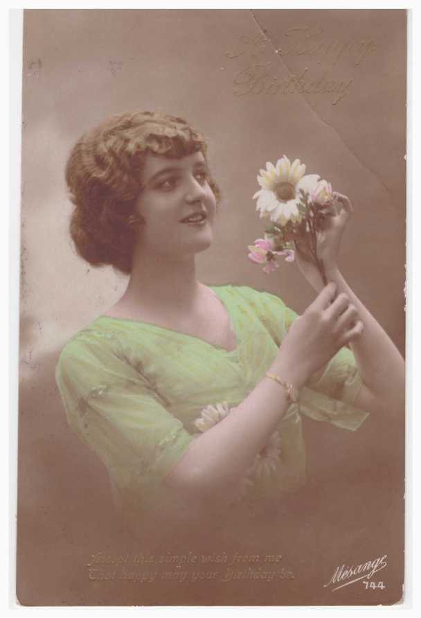 a woman in a green dress holds a small bunch of flowers