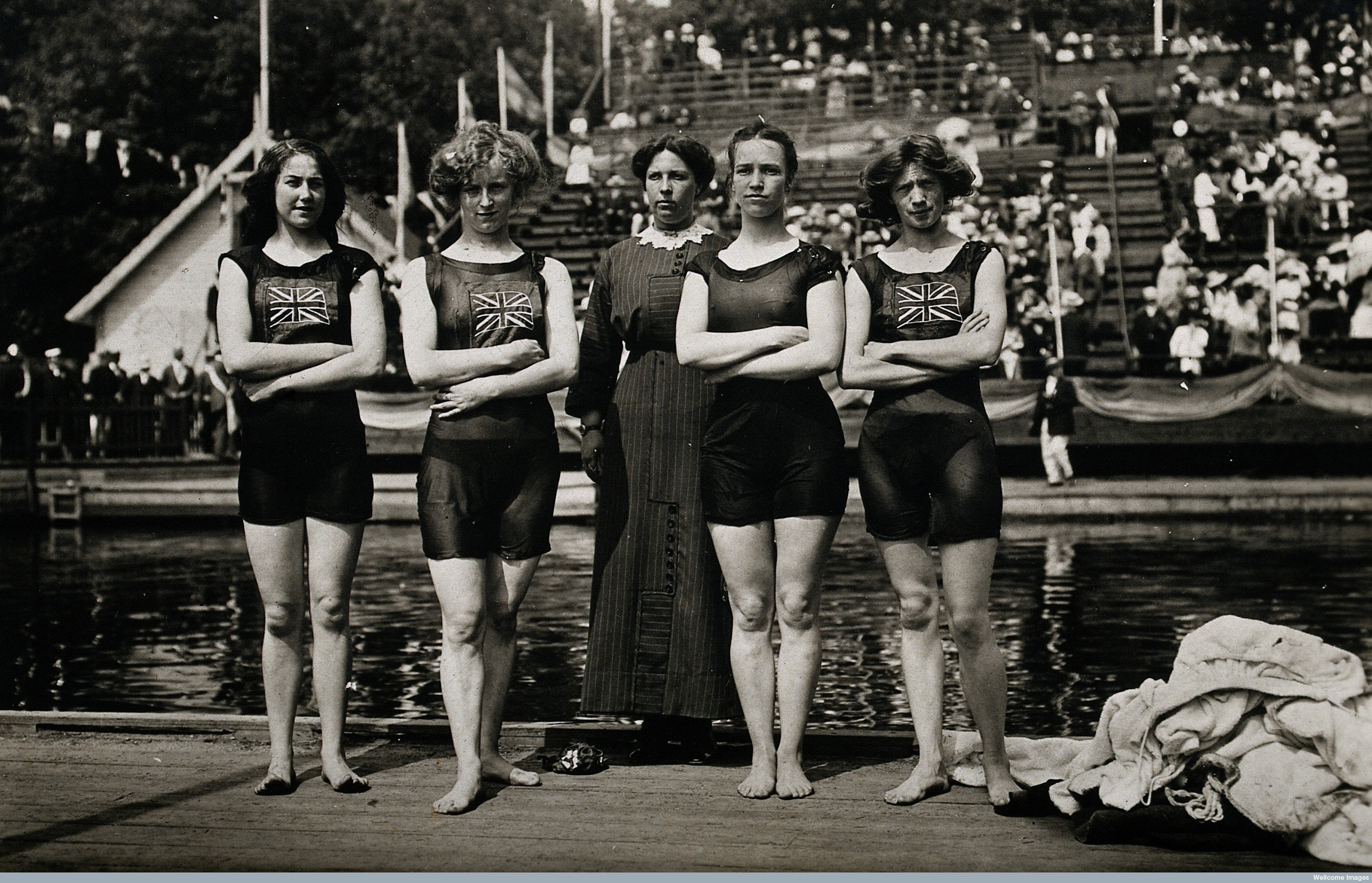 four female swimmers standing by a pool 