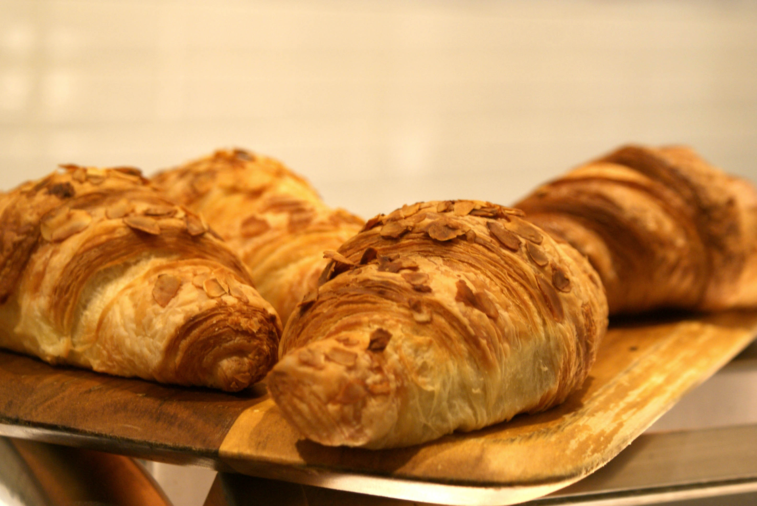 colour photograph of several almond croissants on a wooden tray.