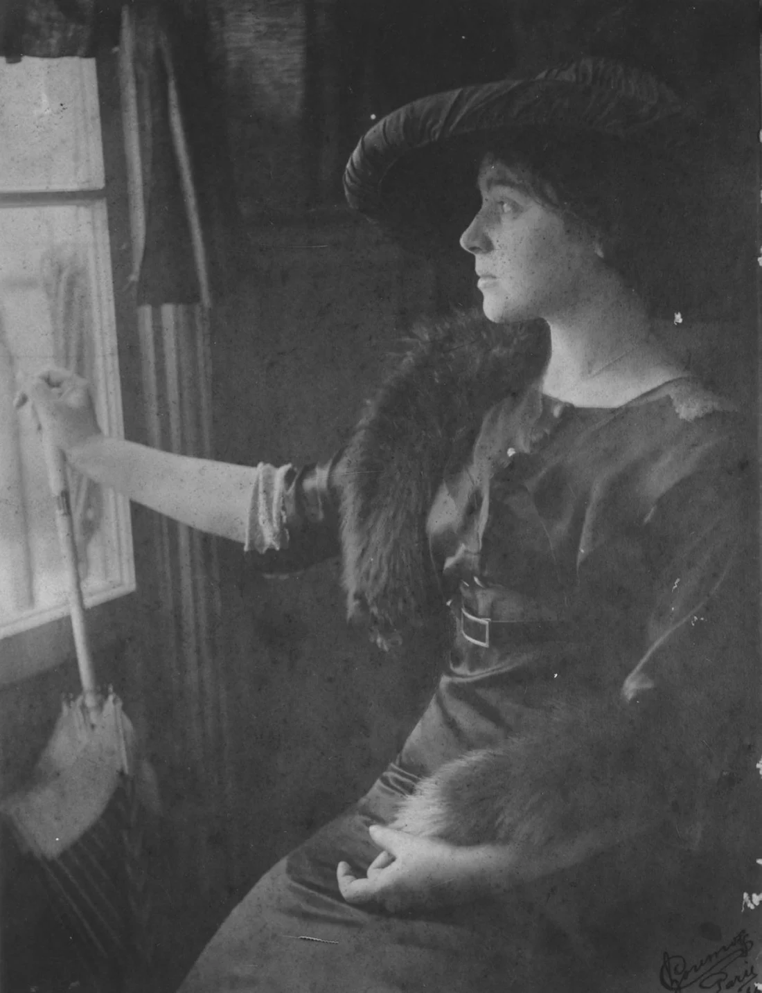 black and white photograph of Mela Muter who holds an umbrella and looks out a window