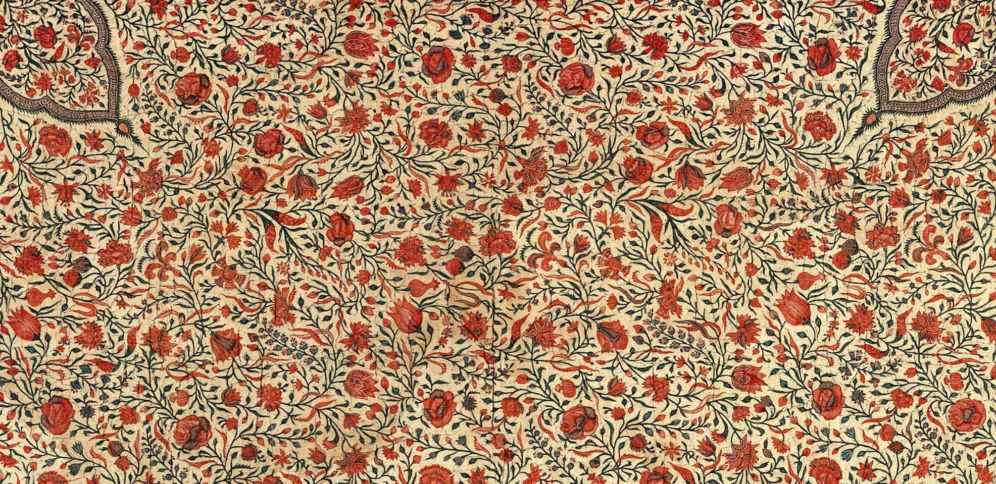 colour photograph of a beige textile, with mostly red pattern of flower vines.