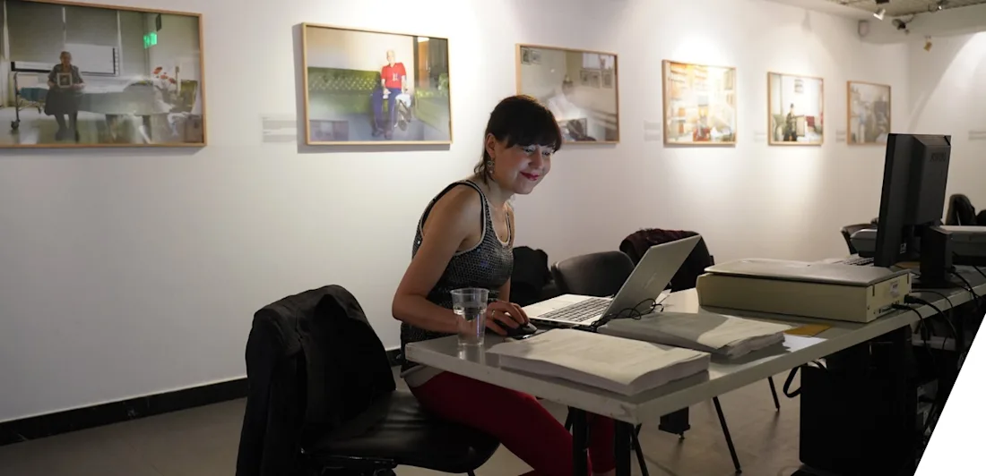 Sofie Taes seated at a table with a computer in a gallery