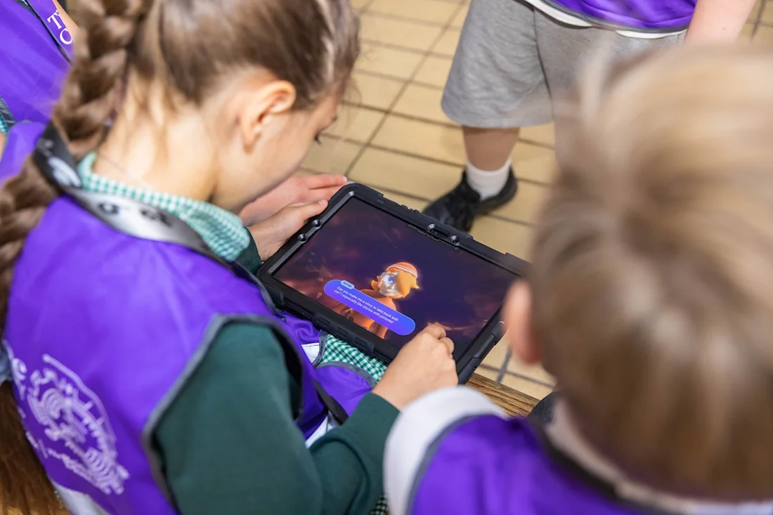 Children play with a Time Odyssey avatar on a tablet. 