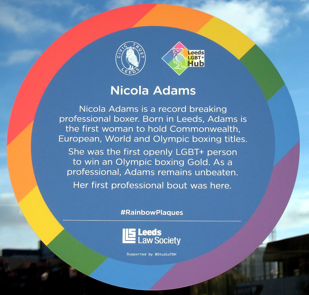 Photo couleur d'une plaque circulaire avec un motif arc-en-ciel sur les bords et un texte sur Nicola Adams.

