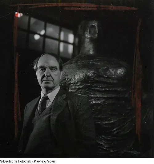 black and white photograph of Henry Moore in front of one of his sculptures