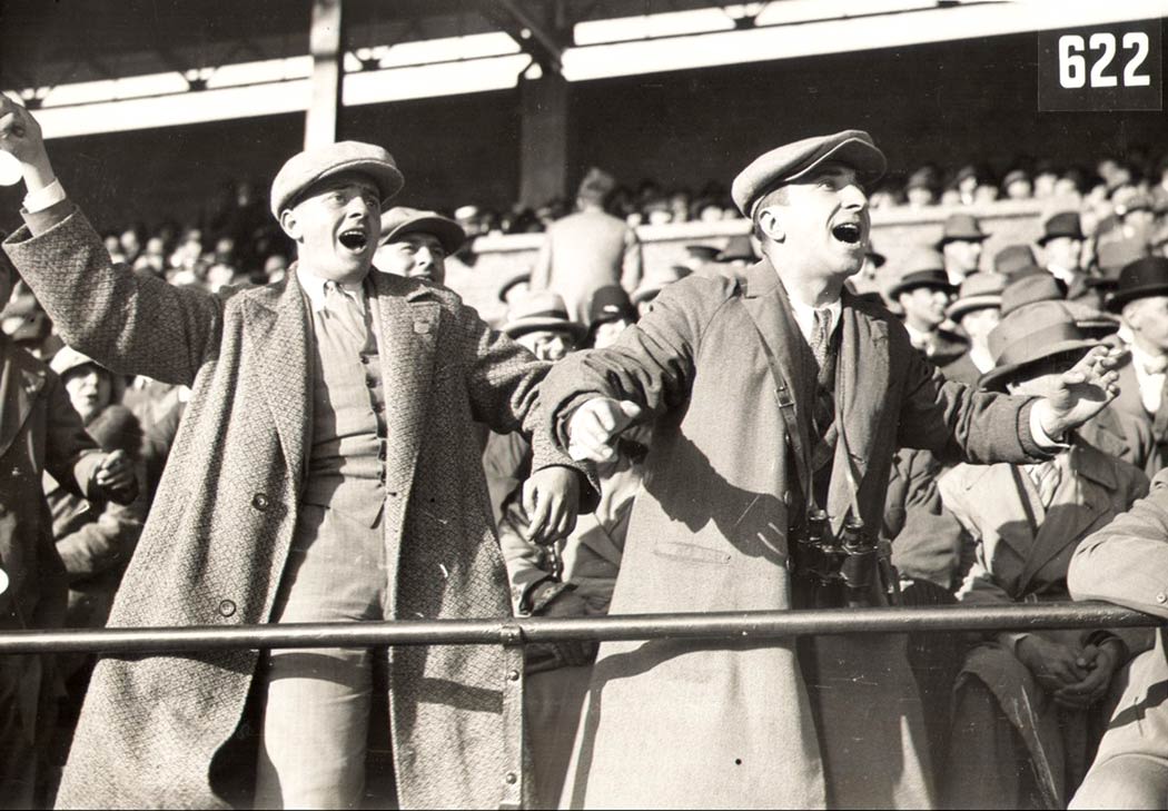 black and white photograph, two men in the audience watching sports react with surprise.