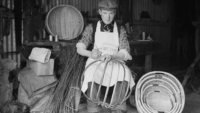 black and white photograph of a man weaving a basket