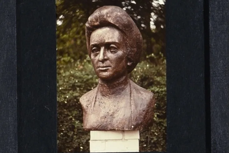 a bronze bust of Rosa Luxemburg stands on a pedestal in a park. Her halflong hair bobs around her face, she stares defiantly into the distance.