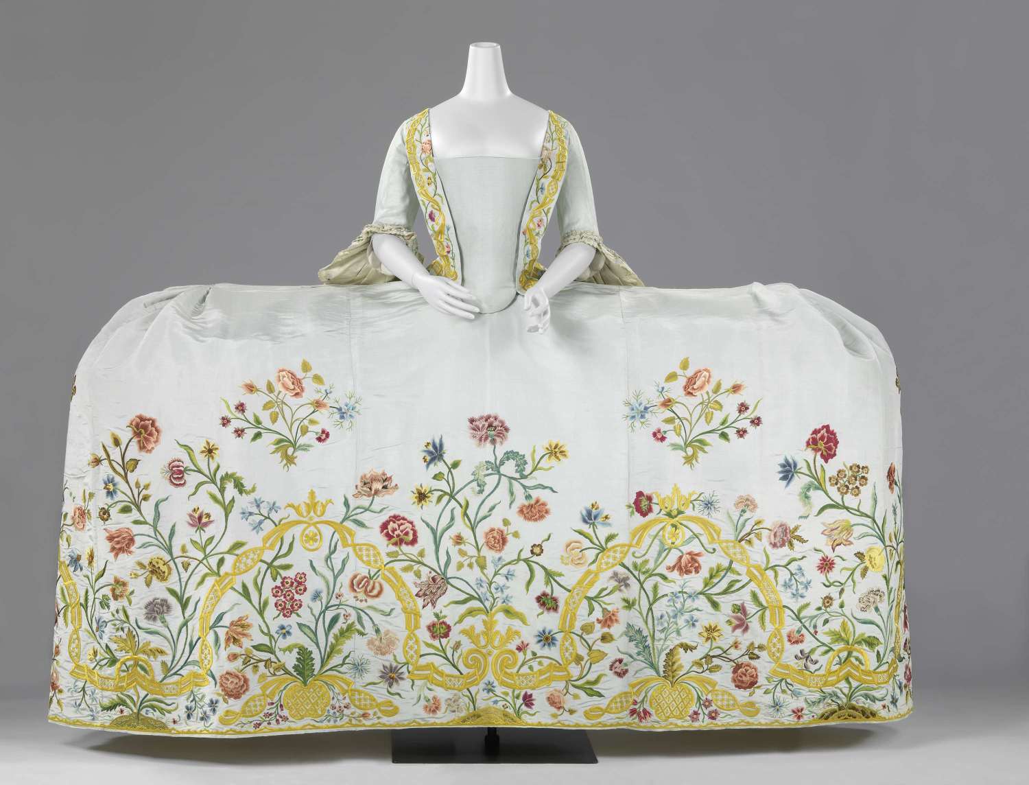 colour photograph of a white dress with a very wide skirt, with floral embroidery details.