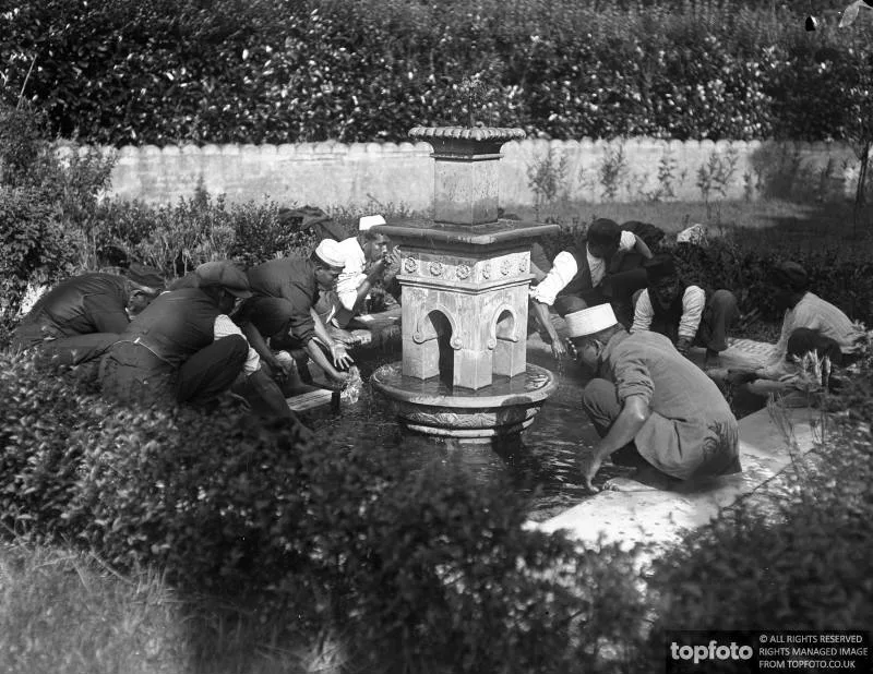 black and white photograph, people kneeling at a fountain in a mosque