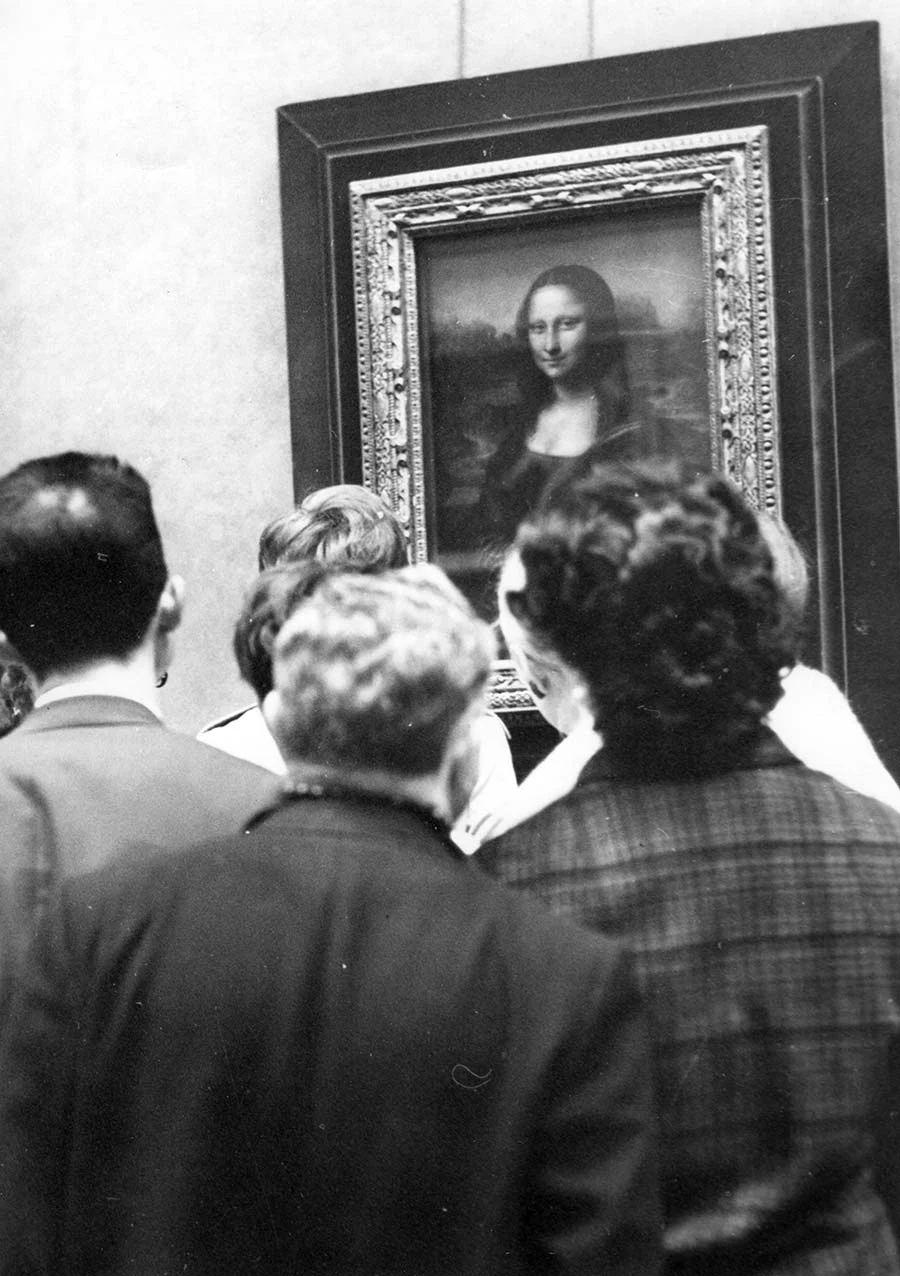 black and white photograph of a group of people in front of the Mona Lisa painting