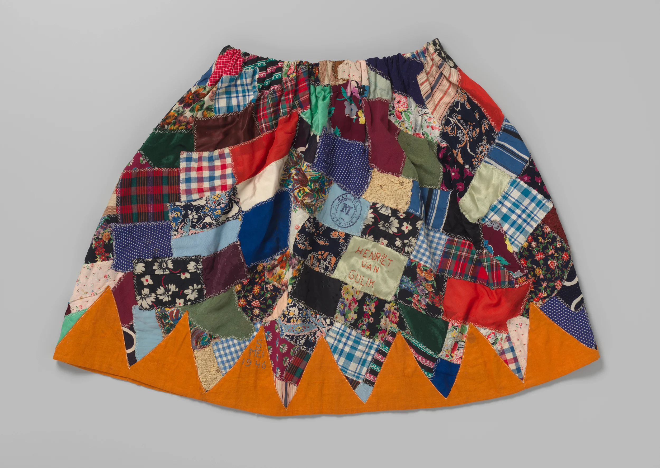 Colourful skirt composed of numerous patches of fabric embroidered with '19 Dec. 1935', '16 April 1945', 'Henrietta van Gulik' and stamped 'National Party Skirt..., 1947'.