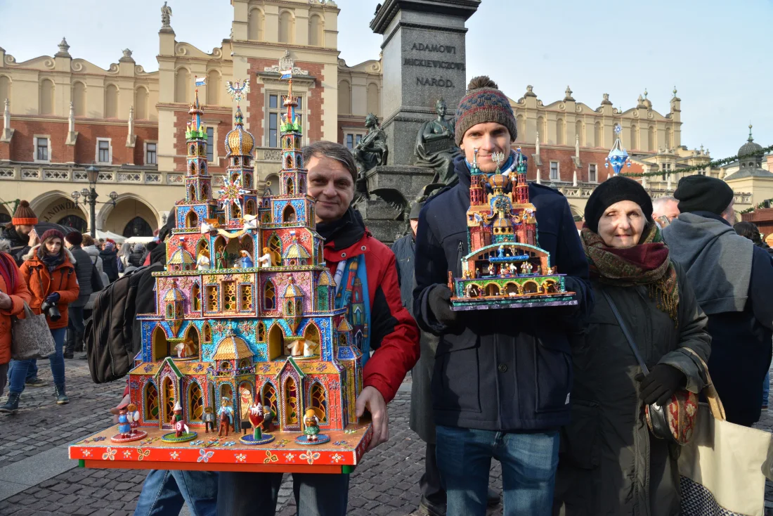 two men hold colourful nativity scenes on the main square of Krakow