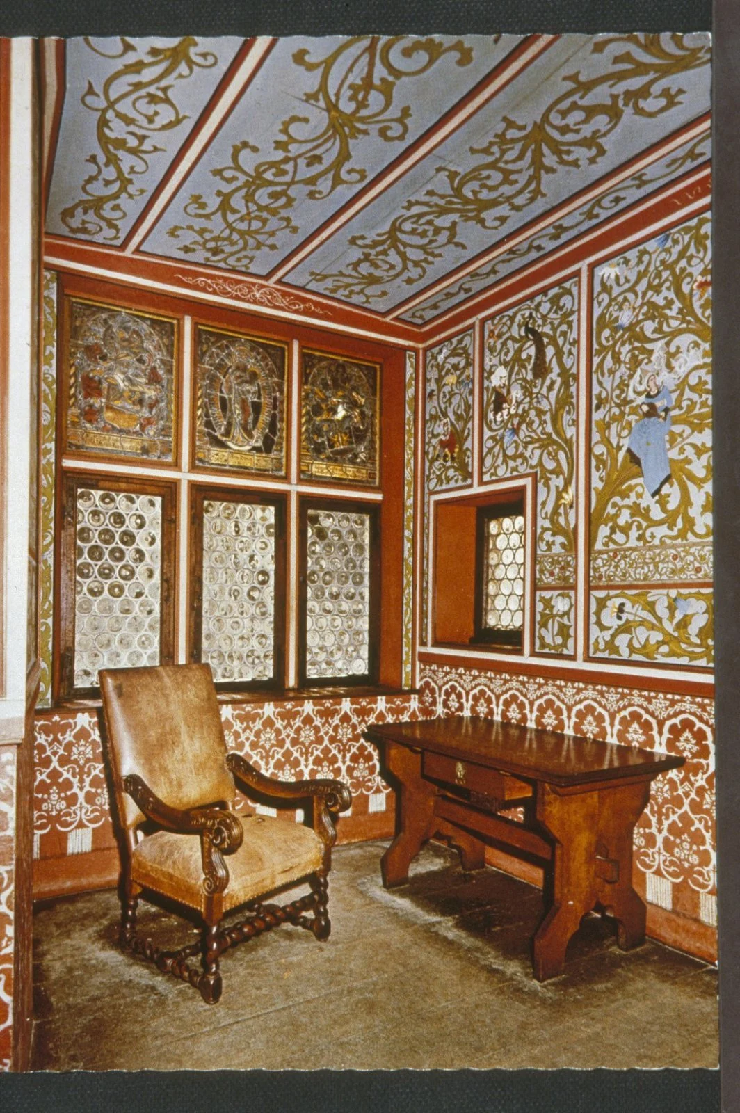 colour photograph of an interior room with richly decorated wall and ceiling paintings, and chair and table