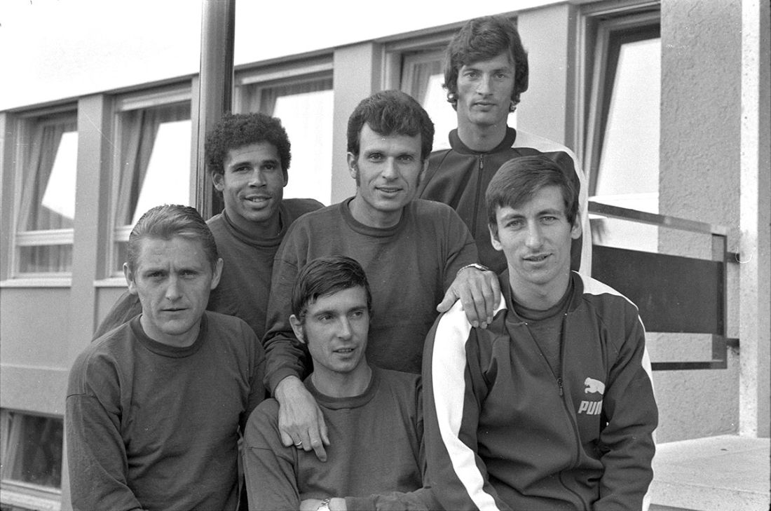 Photographie en noir et blanc de six hommes, des footballeurs portant des pulls
