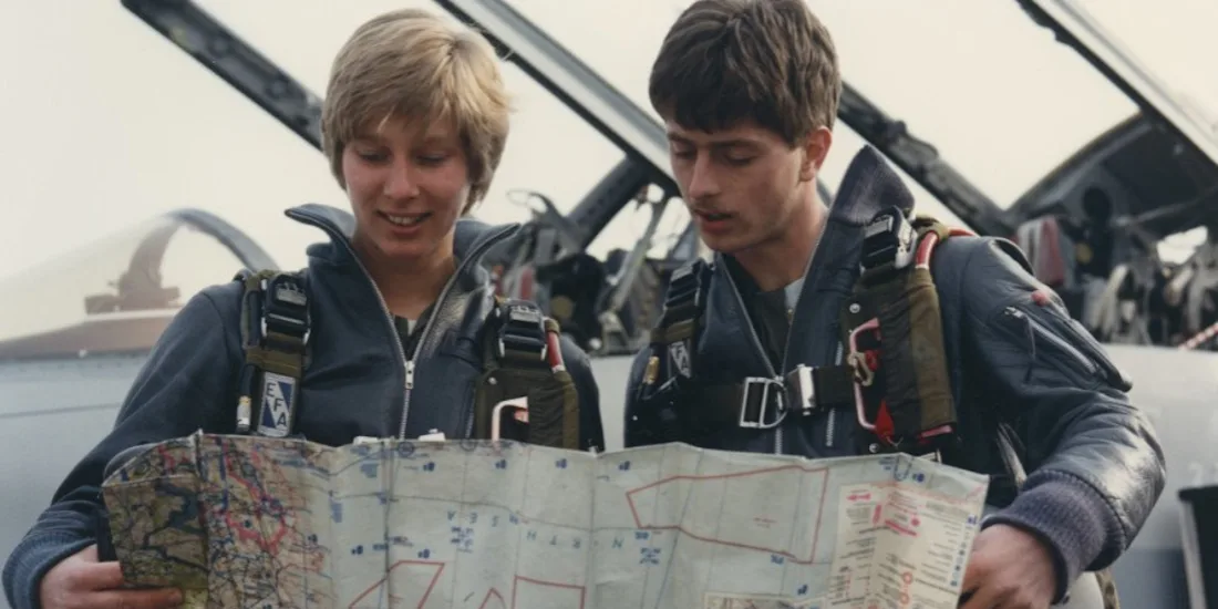 Two pilots, a man and a woman, look at a map