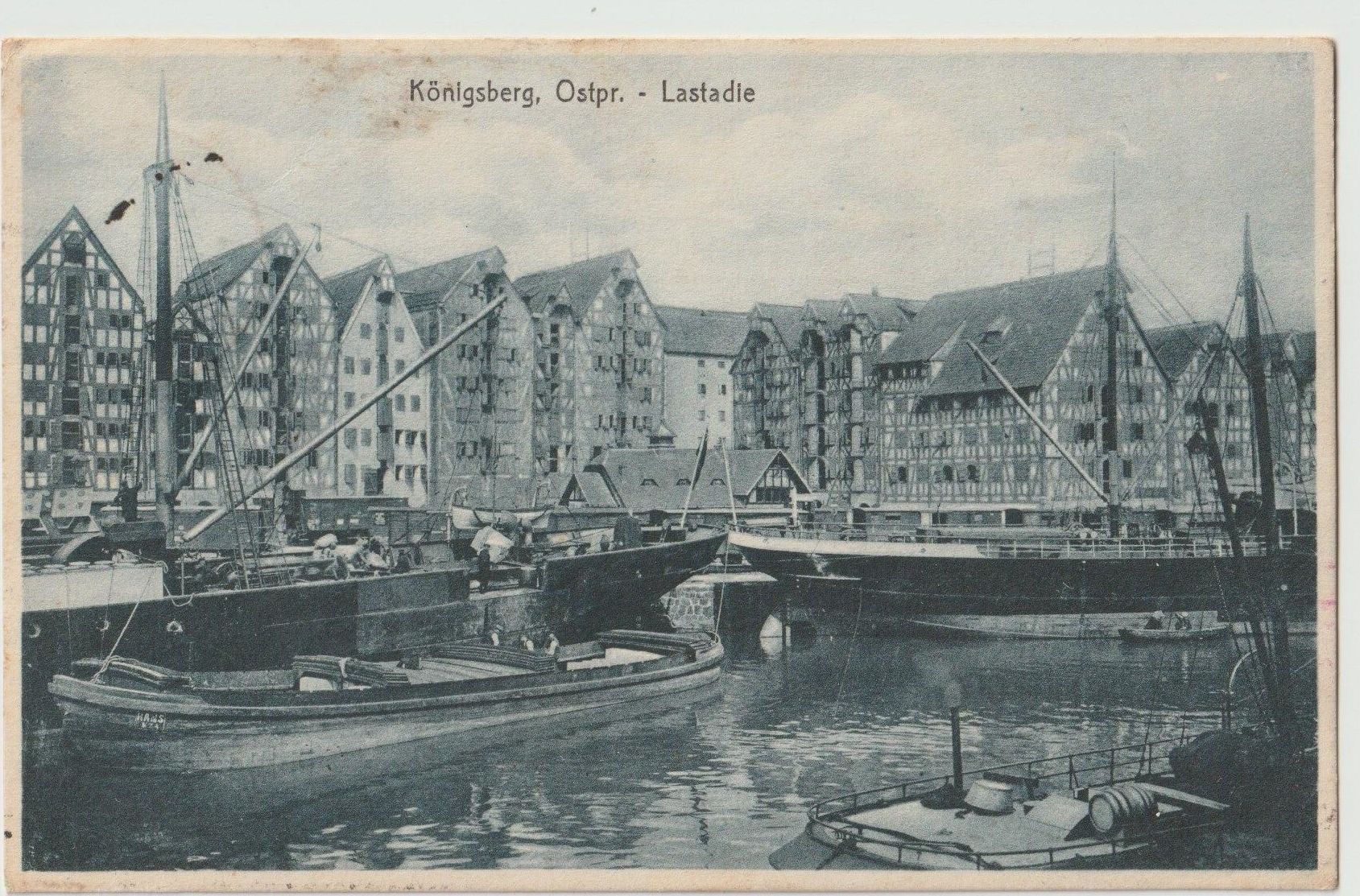 Harbour with boats and barges, with buildings in the background
