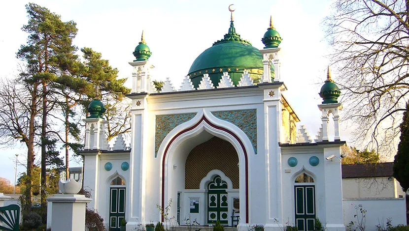 colour photograph, a white mosque building with mosaic panels and green domes