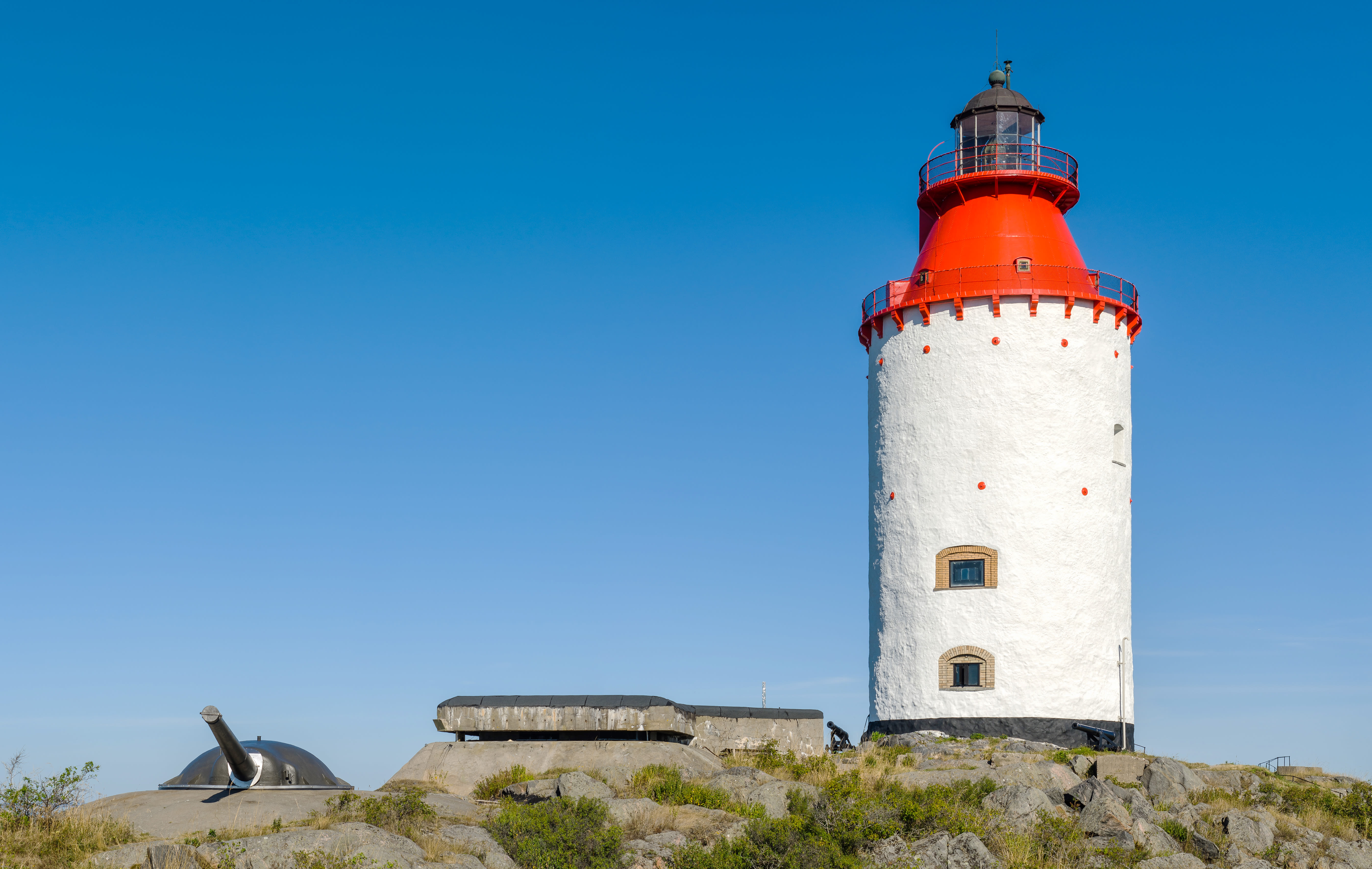 colour photograph of a white and red lighthouse against a bright blue sky