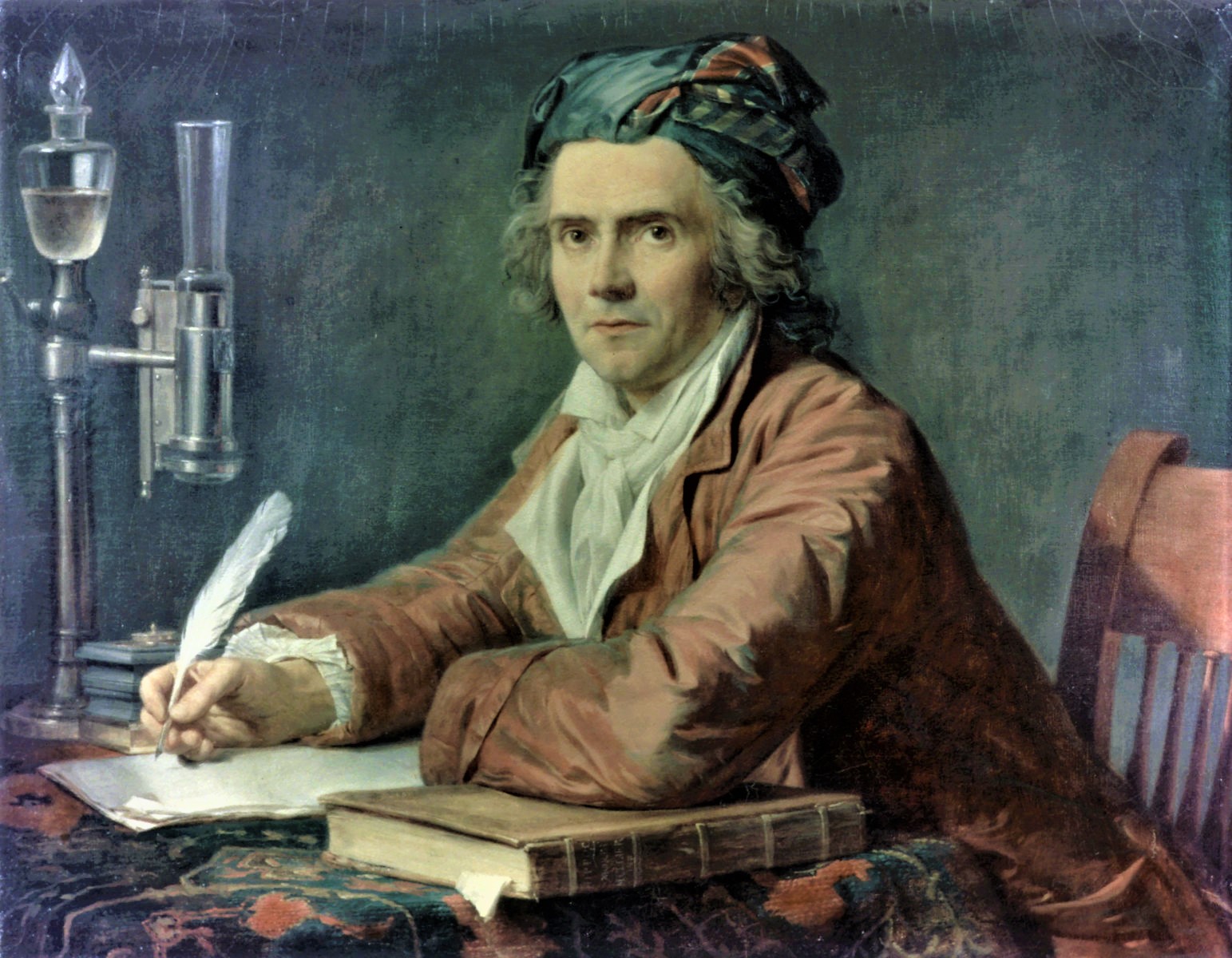 Portrét Alfonse Leroye, sedícího u psacího stolu v červeném oděvu a v modrém a červeném turbanu. Alfons drží brk a zírá přímo na diváka.