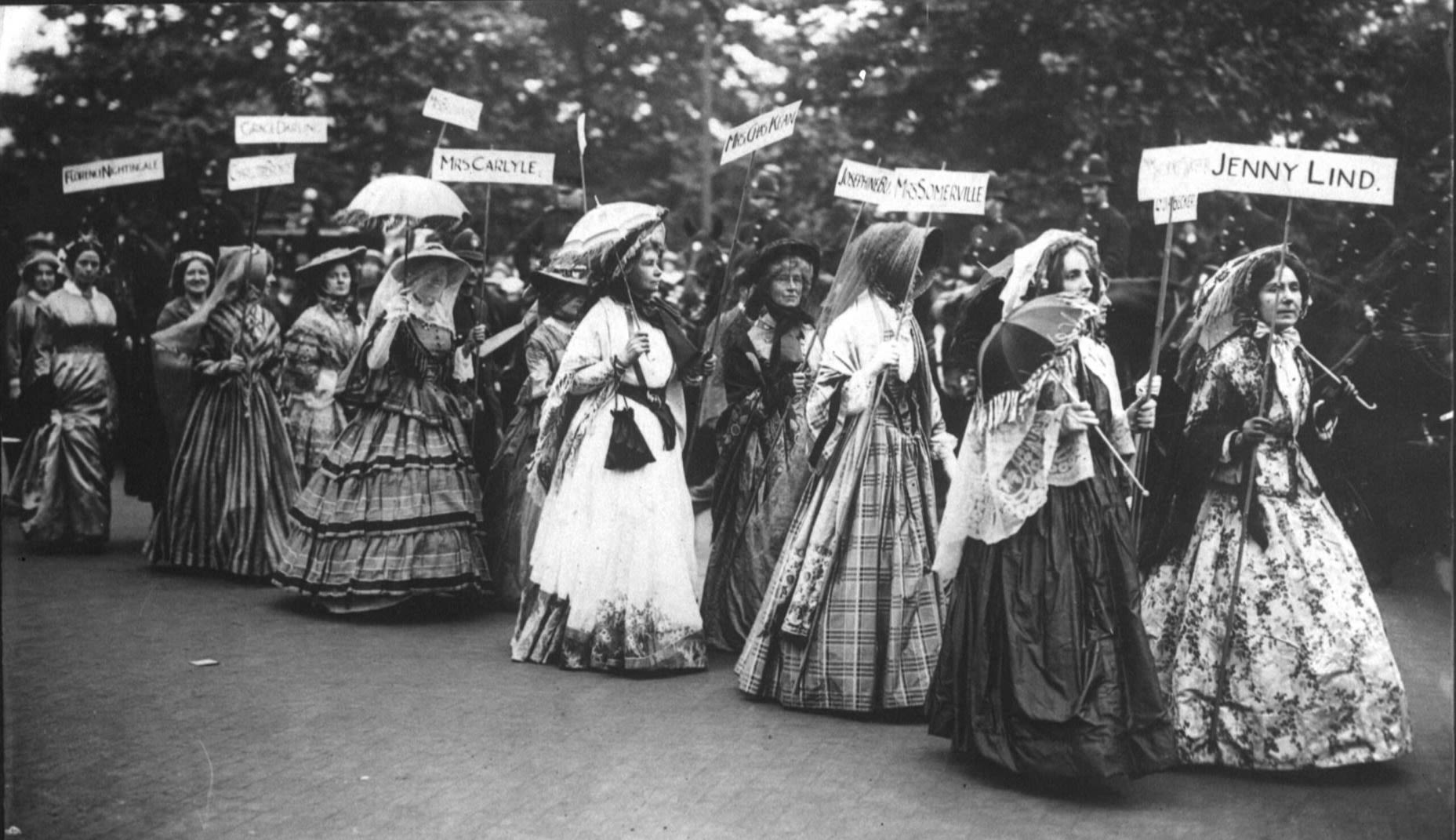 Photographie en noir et blanc de suffragettes à Londres, portant des pancartes indiquant les noms de Jenny Lind, Mme Somerville, Mme Chas Kean, Mme Carlyle, Florence Nightingale