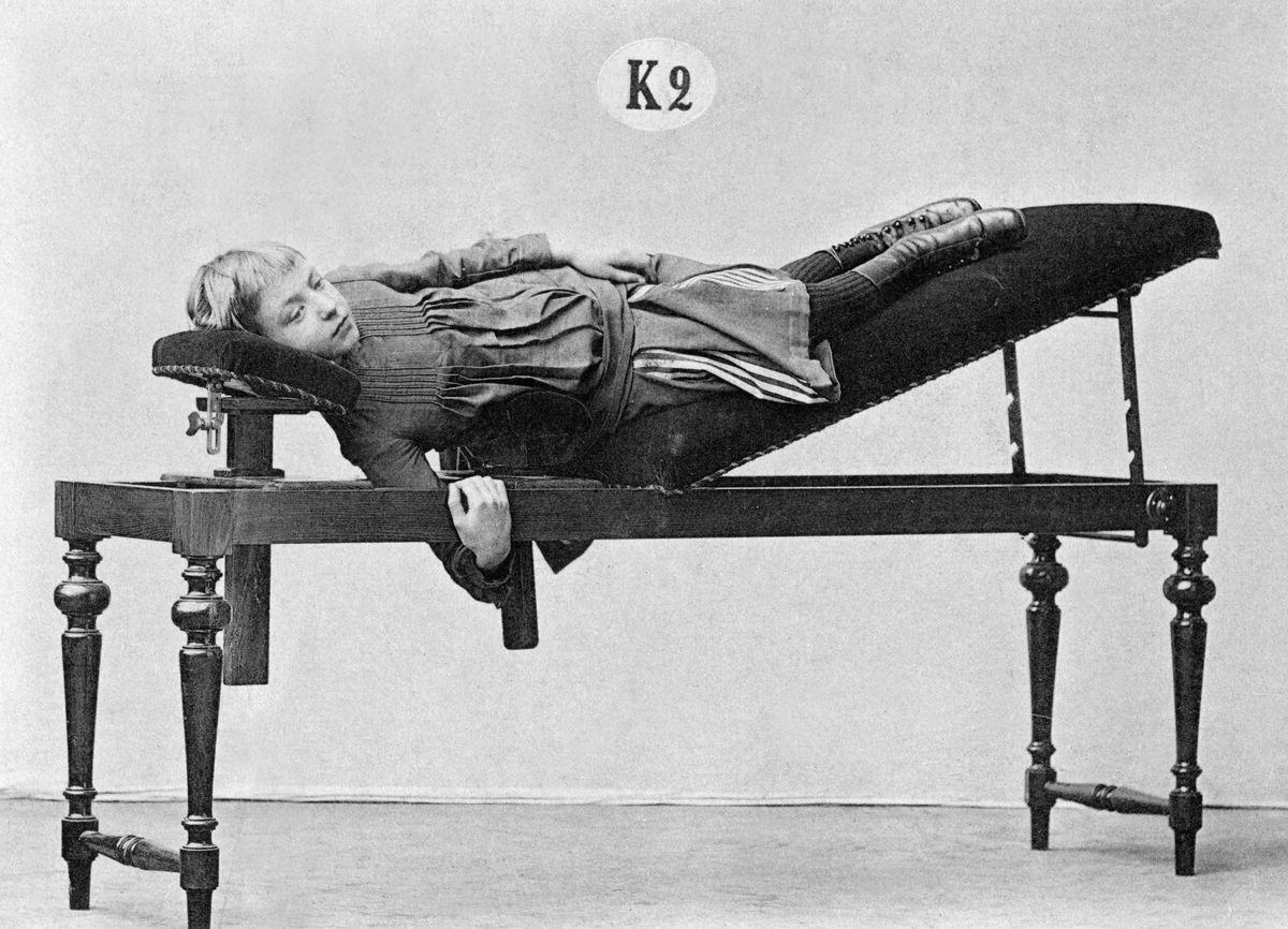 Black and white picture of young girl laying on massage table elevating her legs. 
