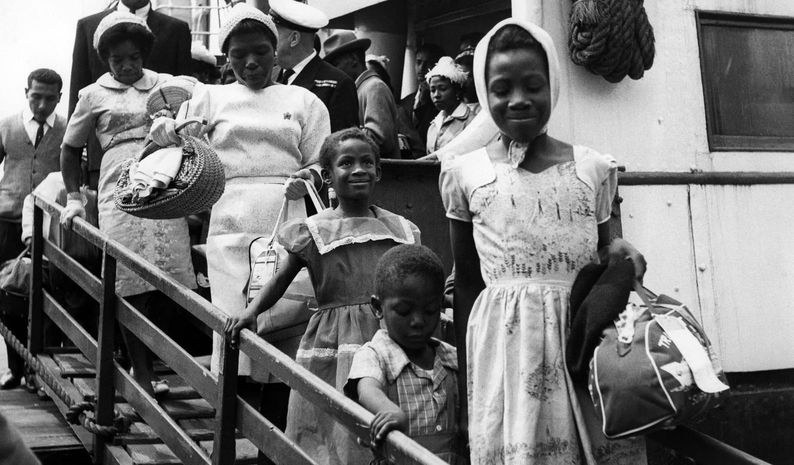 black and white photograph of several black people descending a gangway from a ship