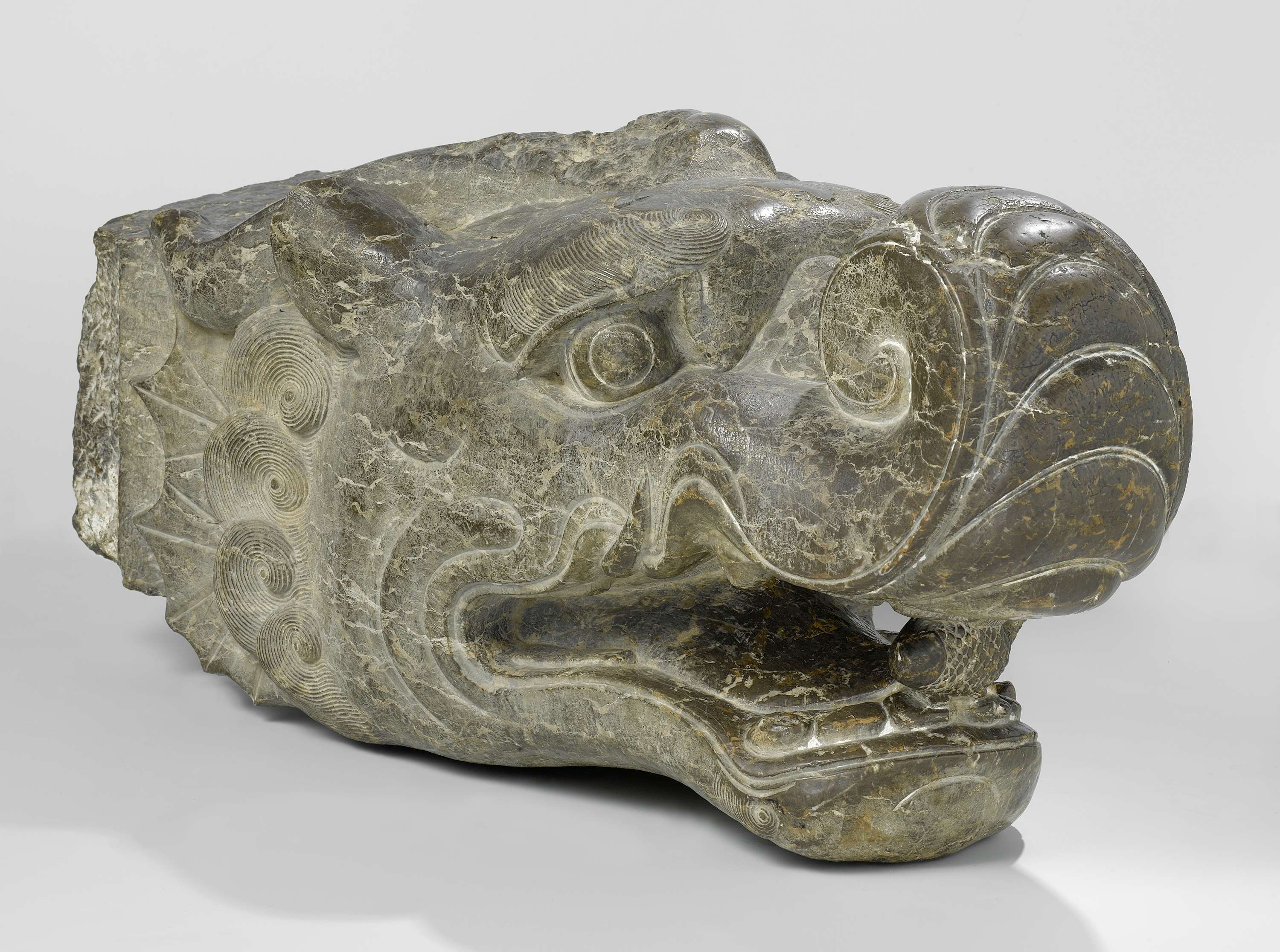 Stone head of a dragon with a fish in its mouth