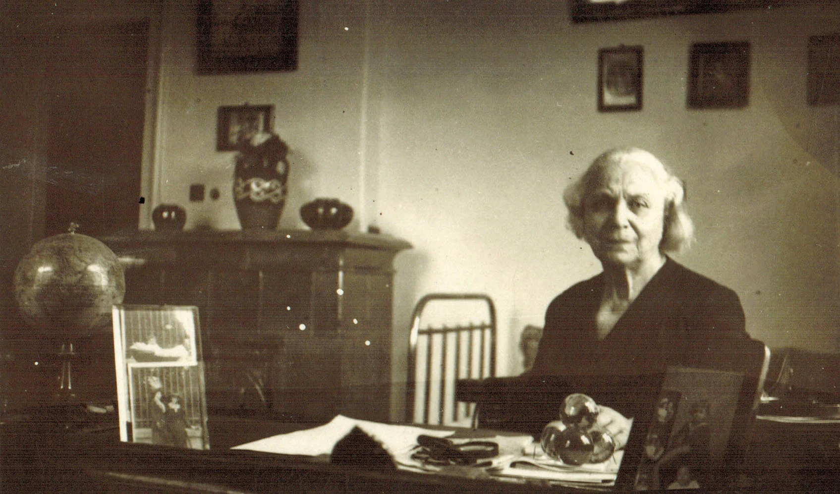 Ekaterina Karavelova sitting at a desk with papers and objects.
