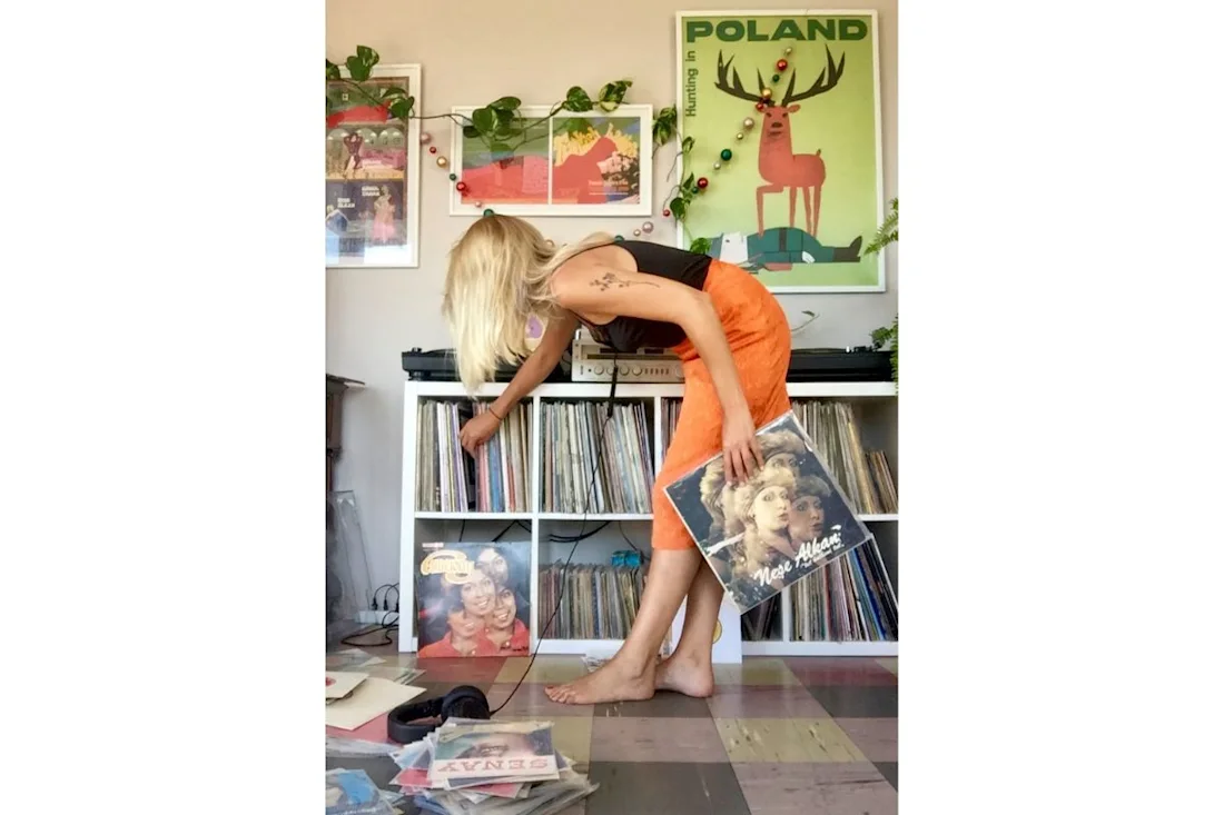 Kornelia leans over to pull a record from a shelf.