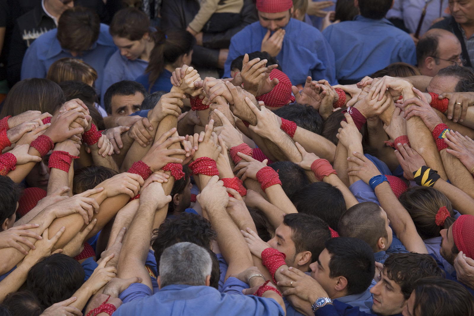 colour photograph of people beginning a human tower, each with their arms out-stretched