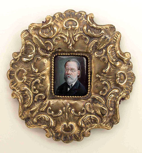 small painting of bearded man wearing glasses in an ornate gold frame
